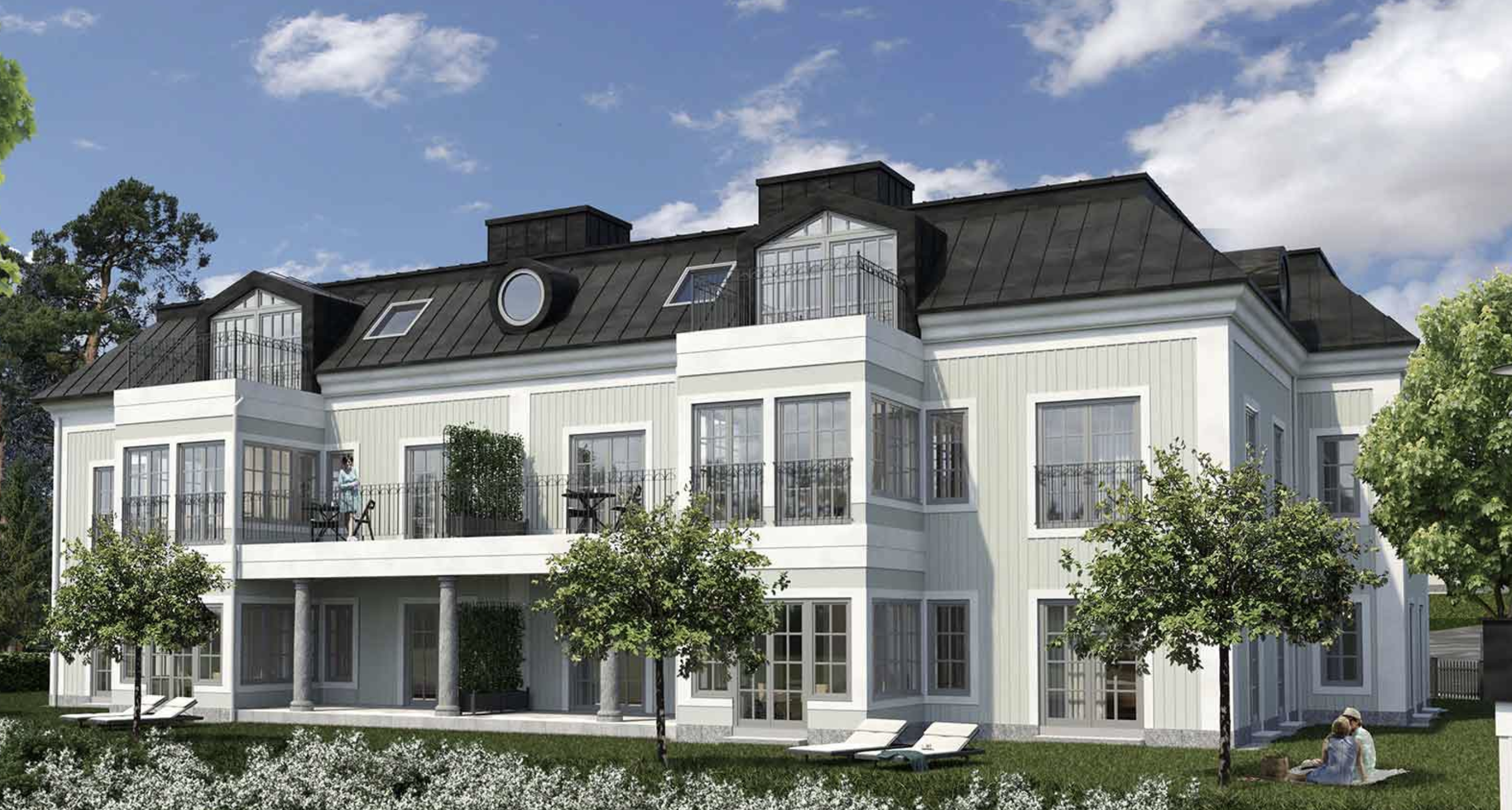 Ljust bostadshus med balkonger, svart tak och grönskande trädgård i Steninge Slottsby.